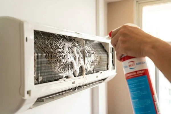 Coolbest Aircon technician spraying chemical solution on evaporator coil in Singapore HDB flat